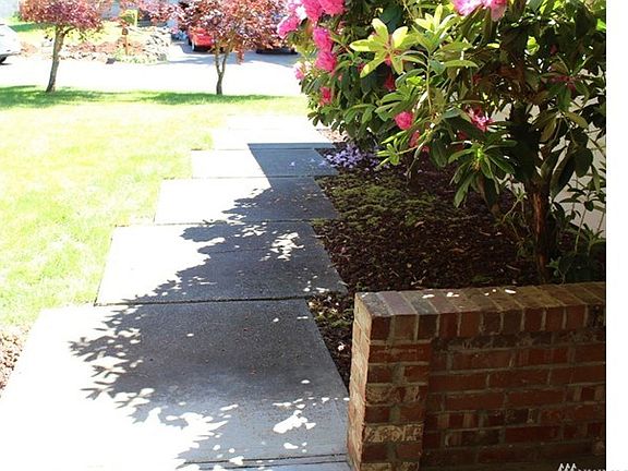 Sidewalk leads to covered entry with brick accents.