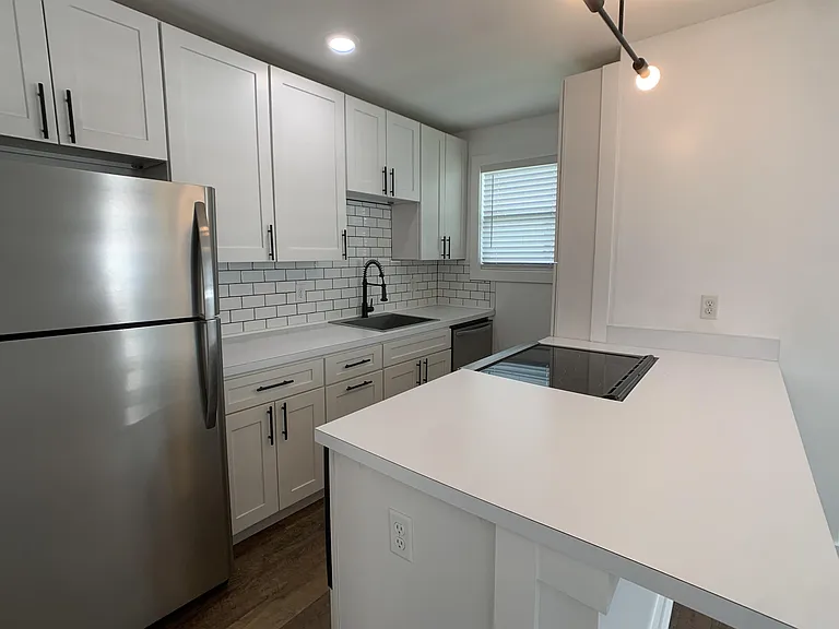 White Shaker kitchen cabinets, with stainless steel appliances and glass topped slide-in stove/oven.