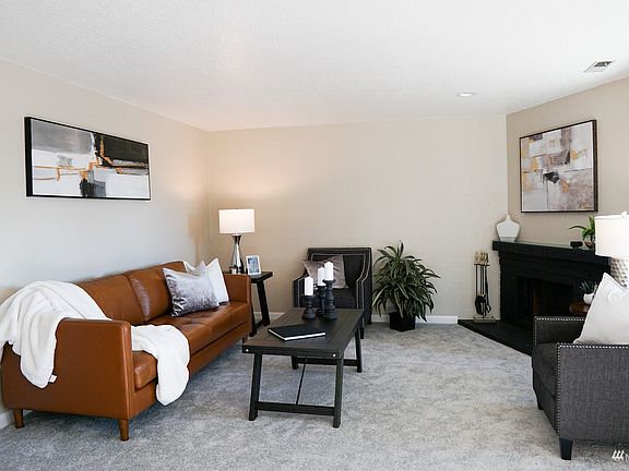 Cozy living room is adorned with a wood-burning fireplace.>
