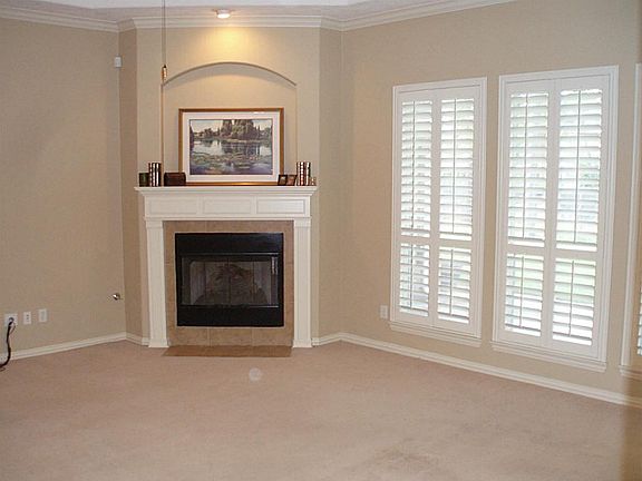 This shows half of the main living area with gas fireplace, spotlight on mantle and plantation shutt
