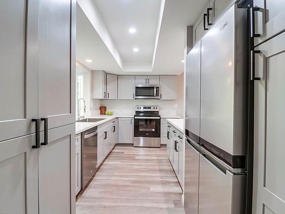 Full size stackable washer/dryer tucked in cabinets on left. Brand new refrigerator and pantry to the right.