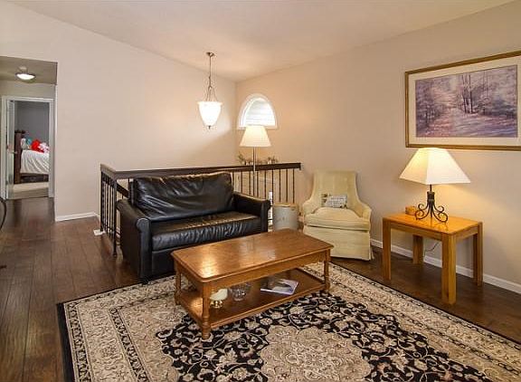Another view of the living room looking towards the front stairs and hallway leading to bedrooms and bathroom.