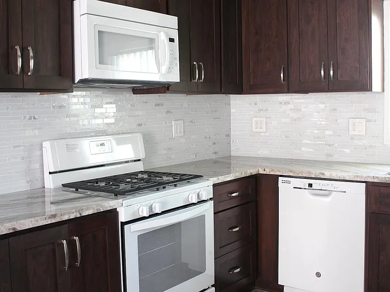 KITCHEN WITH STOVE, MICROWAVE, DISHWASHER AND BRAND NEW REFRIGERATOR.