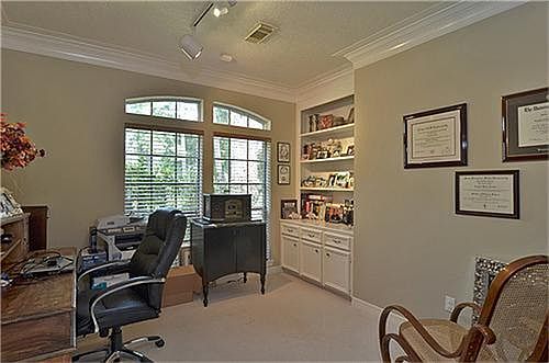 Study or home office has crown molding, French doors, built ins and track lighting.