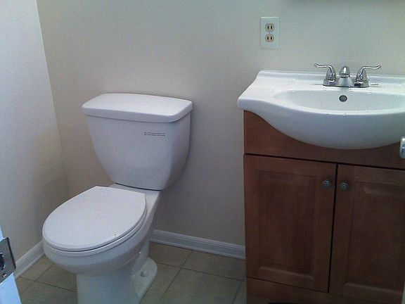 Bathroom near the entrance has a new toilet and sink with underneath cabinetry