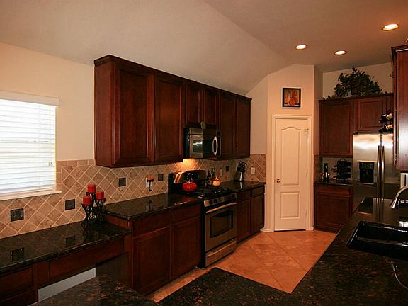 Another view of the kitchen, with beautiful granite counters, recessed lighting, and built in desk.