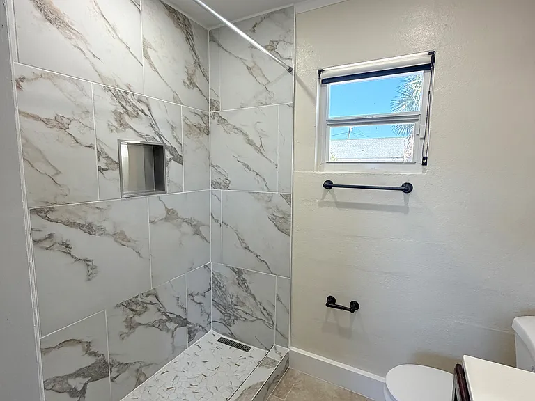 Bathroom with a newly installed standing shower with full tile surround. (Angle 1)