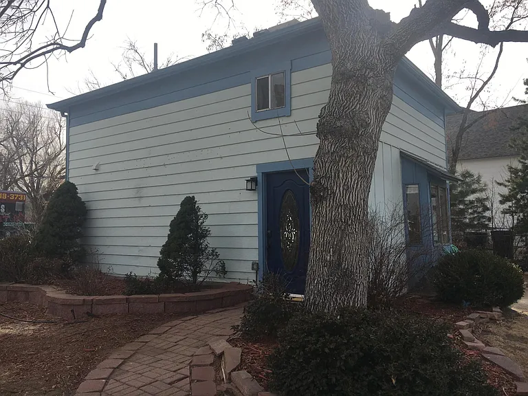 Exterior of building with front door (leads to living room). Large ash tree provides nice shade in summertime.
