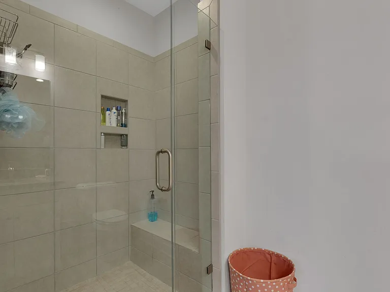 Walk-in tile shower with bench seat and framless shower door