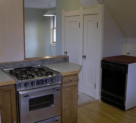 View to SW from kitchen, over landing at top of stairs, to dining space that's part of living room. Movable dish washer on right. Renters can use, but must be moved next to sink to use it. If renters not interested in using, it can be moved out of ki