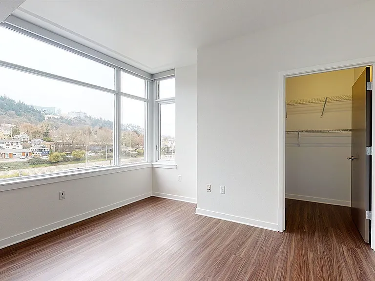 Spacious apartment bedroom with large closet and wood-style flooring.