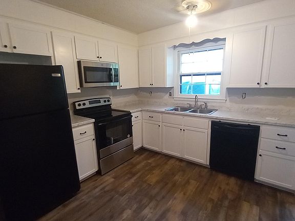 Kitchen with new electric range and microwave and new countertops and newly painted cabinets.
