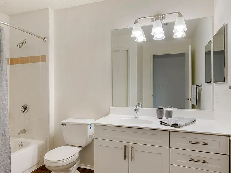 Renovated Package I bath with white cabinetry and hard surface plank flooring
