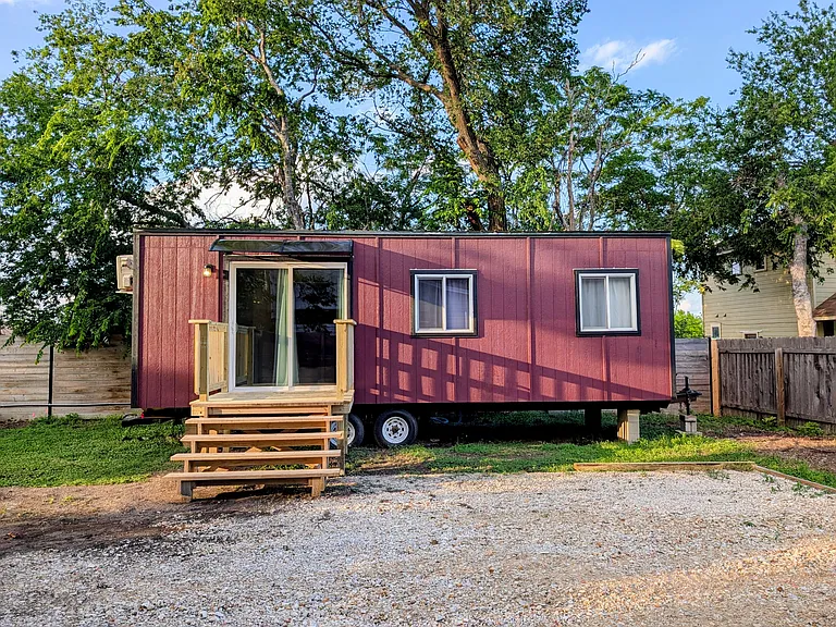 Front of tiny house with small porch and awning. Teo dedicated parking spaces right in front of the tiny house.