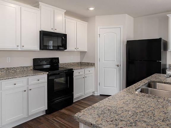 Spacious granite countertops and large white cabinetry make this kitchen ready to use