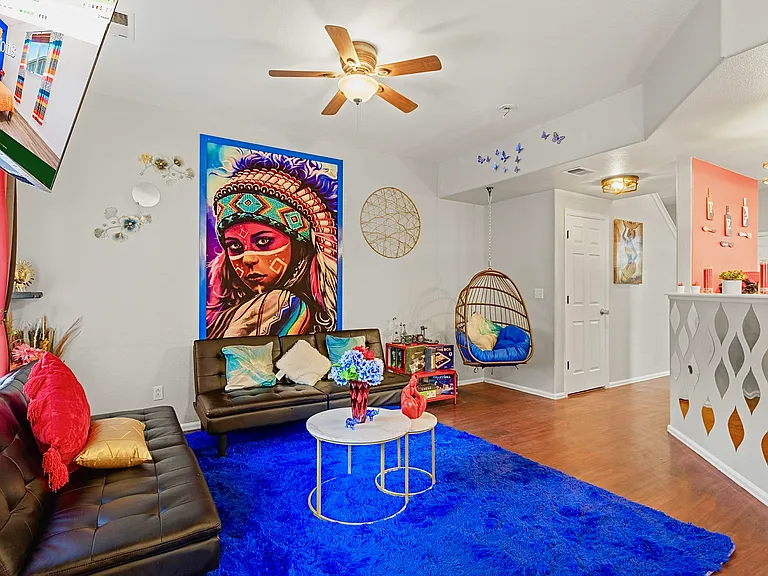 Spacious and eclectic living room with a cozy seating area, a unique hanging chair, and a vibrant Native American-inspired tapestry. Perfect for relaxing and unwinding.