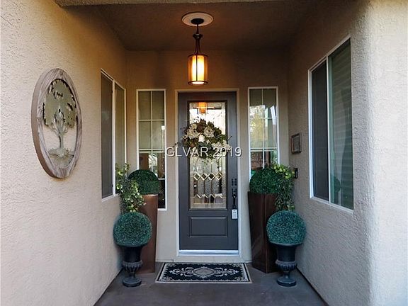 Finished concrete portico entry leads to custom door with glass insert.