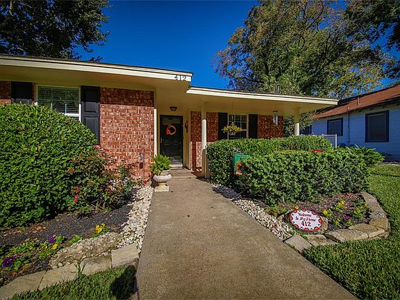 Lush landscaping surrounds the front entrance to this home...