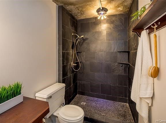 Renovated shower has lots of shelves and a customized pedestal toe shelf for shaving your legs.