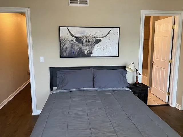 Comfortable bedroom featuring a queen-size bed, nightstand with lamp, and easy access to the hallway and adjoining bath.