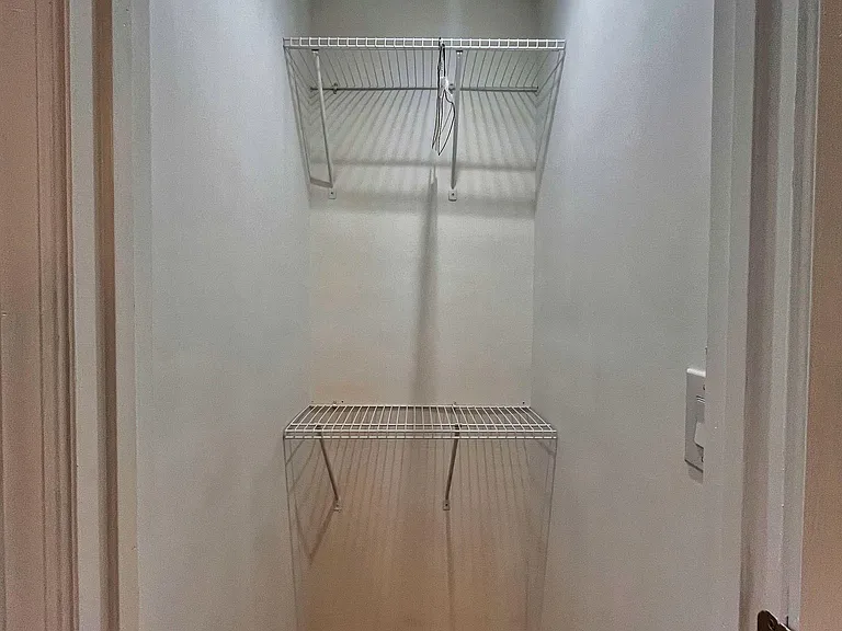 Dedicated walk-in closet with double wire shelving for easy organization of clothing, shoes, and storage bins.