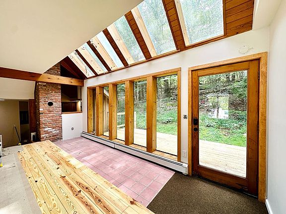 Living room with windows facing secluded back yard with woods, hill and wildlife.