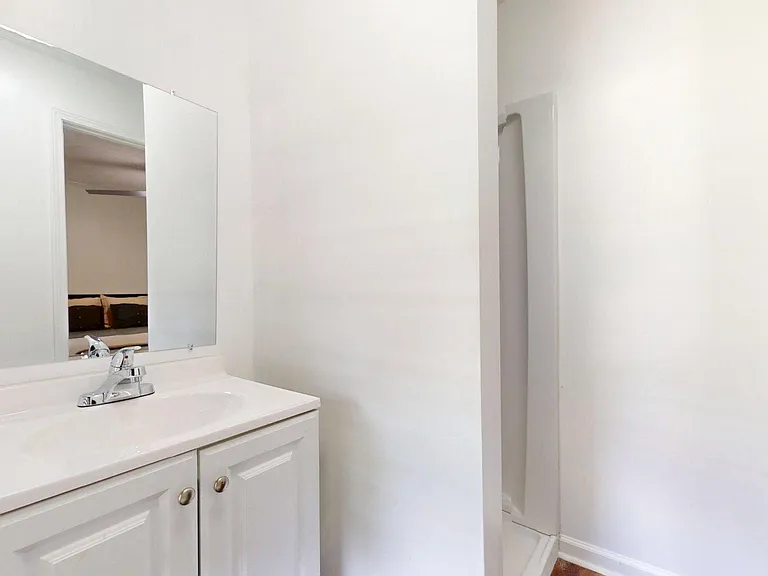 Clean bathroom vanity with wide mirror and ample counter space, located just outside the shower area for easy daily use.