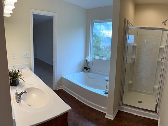 Garden tub with separate shower and double vanity in primary suite