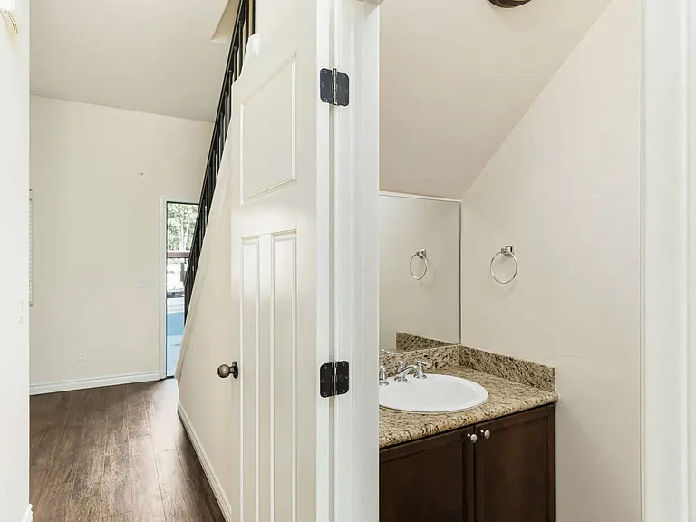 Half bathroom downstairs with dark wood vanity and granite slab top and upgraded fixtures in apartment at The Nines Townhomes in Escondido, California.