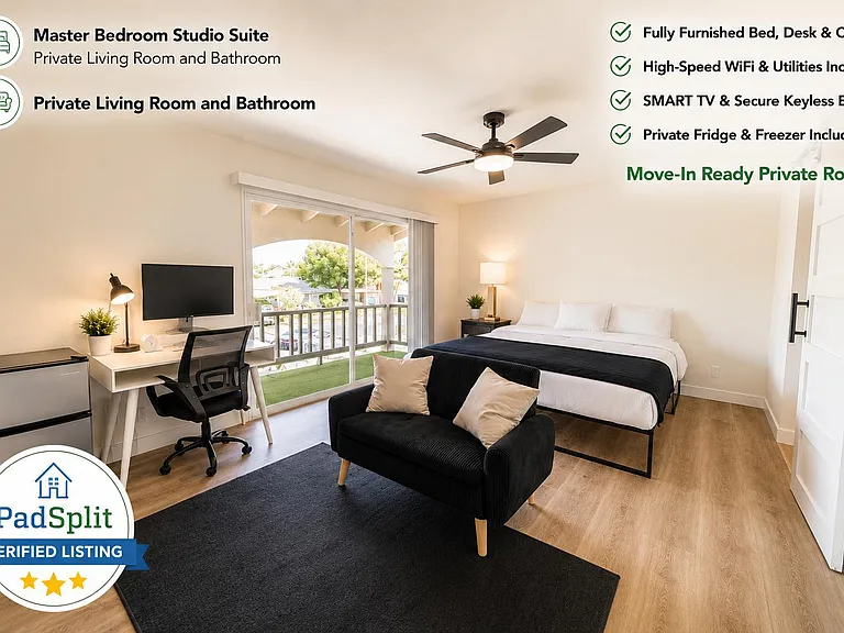 Furnished bedroom suite with a work desk, seating area, mini fridge, and sliding doors to a private balcony.