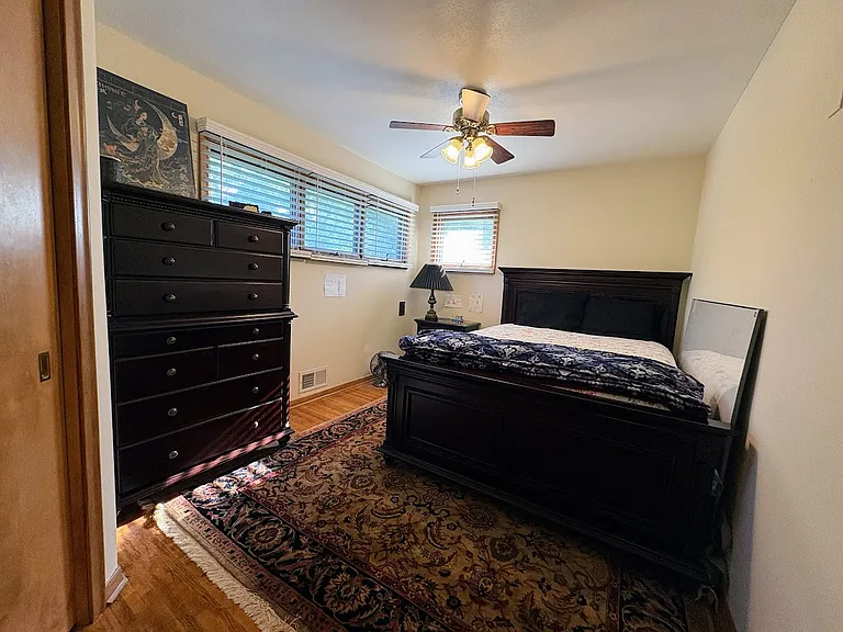 Relaxing Primary Bedroom. Hardwood floors. Ceiling fan. Raised awning-style windows provide privacy and invite in the sunshine.