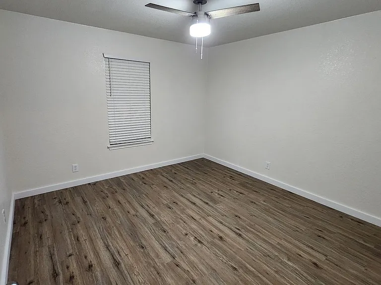 Large back bedroom (12' x 12') with 2" faux wood blinds and modern ceiling fan.