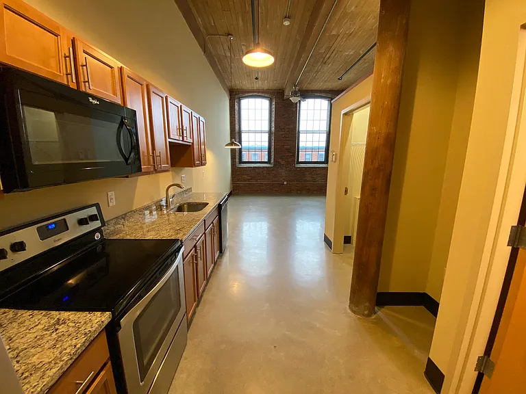 Studio kitchen with bathroom and storage closet on the right, opening to living area