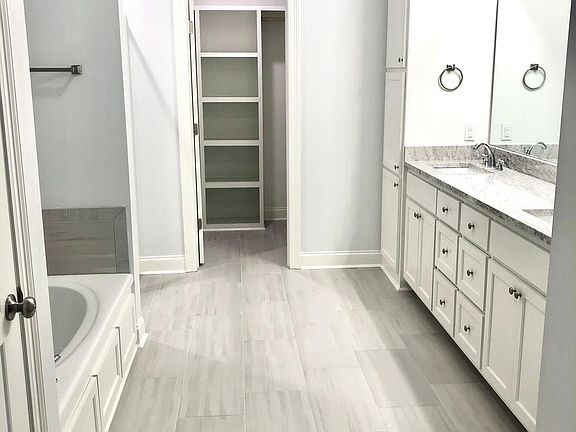 Beautiful French Doors lead into the master bathroom. Spacious with lots of cabinet space, double vanity, upgraded luxury vinyl floors leading into a large walk in closet with built in shoe/purse shelves.