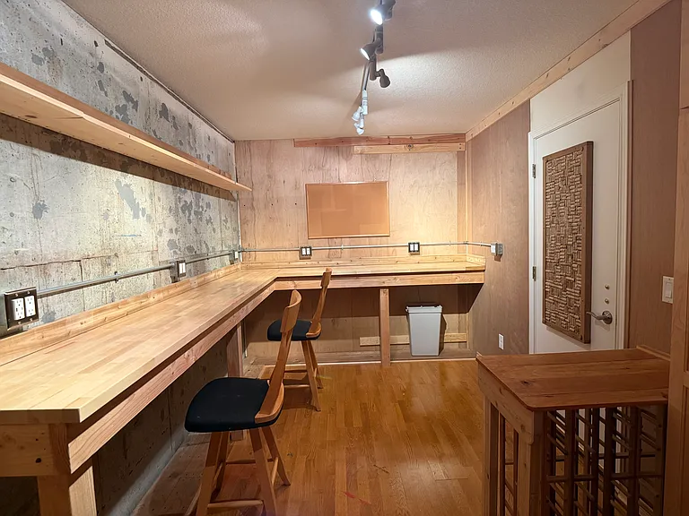 Dedicated arts and crafts studio featuring expansive storage closets on the back wall and a fun display shelf and cork board above.