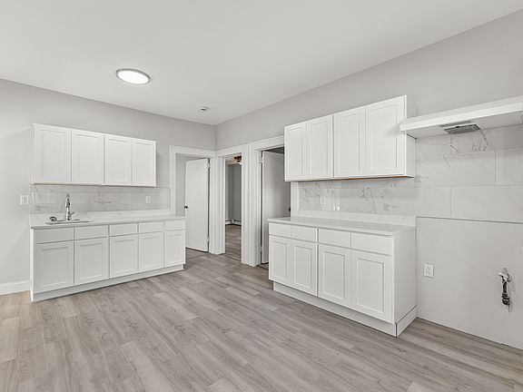 Spacious eat_in kitchen with ample white cabinetry, generous counter space, and tile flooring throughout. Large windows bring in natural light, offering a bright and welcoming space for everyday dining.