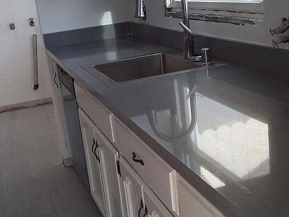 New quartz kitchen counters, sink, faucet, tile floors and laundry hook ups in back ground.