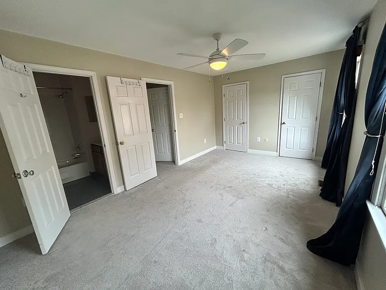 Back facing bedroom on second floor with twin closets, two windows with sun-drenched afternoon light, fan and attached full bath. This is a large bedroom and can easily have a shared home office.