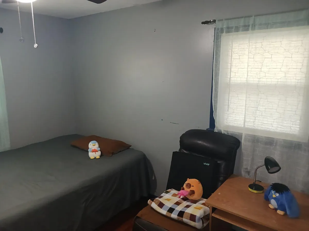 Furnished bedroom with a twin bed, desk and chair, and a large window with curtains for natural light. - Burkhead Dr