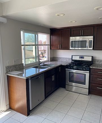 Kitchen with granite countertops, stove, microwave and dishwasher.
