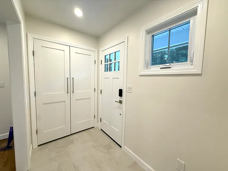 Mudroom off of driveway with heated floors, coat closet, and built-in bench