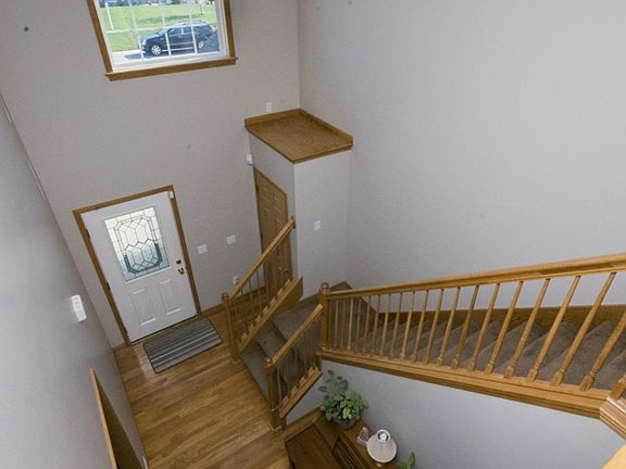 Another view from the second story of this home shows the 18 ft grand entrance with large grid window above the steel entry door which allows plenty of light to shine in. Programmable home alarm system comes with home. Oak shelf above coat closet is a great place to set the stage!