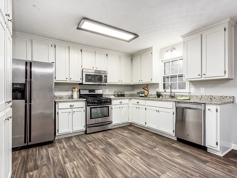 Large kitchen with stainless steel appliances and granite countertops.
