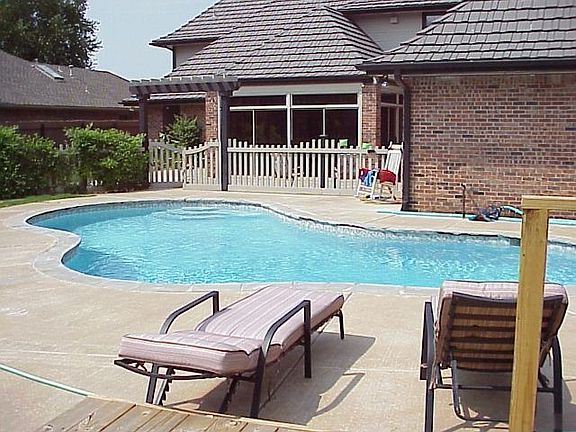 View from wood deck of pool and enclosed sun room on back side of house.