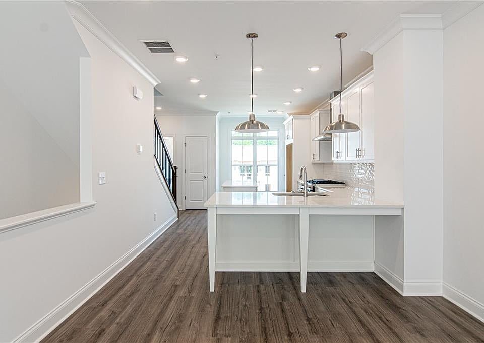 Kitchen featuring white cabinets, LVP flooring, quartz countertops, and plenty of natural lighting.