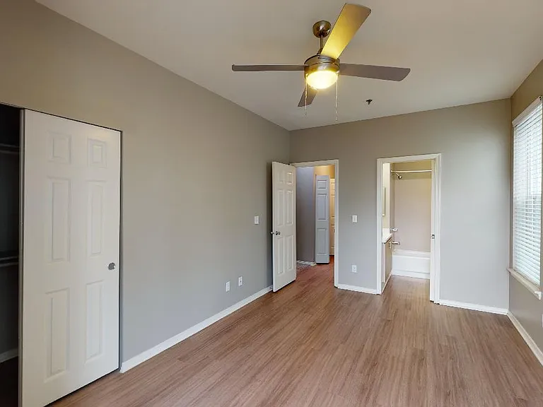 Spacious apartment bedroom with large closet and wood-style flooring.