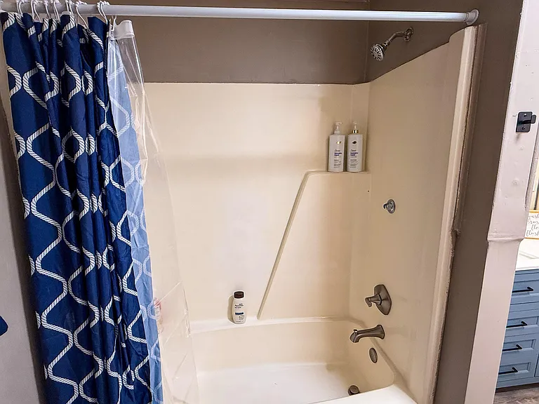 Tub/shower combo with built-in ledge and a shower curtain for added privacy and everyday convenience.