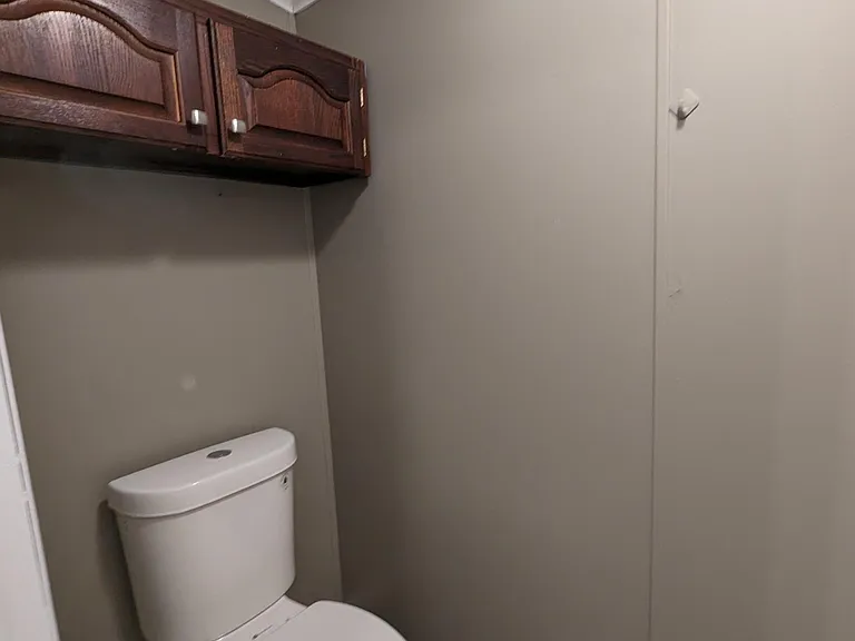 private toilet area with modern toilet, cabinets and separate exhaust fan
