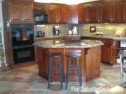 Granite countertops, beautiful wood cabinetry, ceramic tile floor in kitchen.