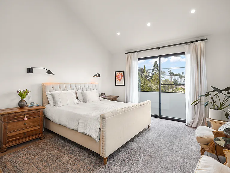 Spacious primary bedroom with balcony overlooking the pool and backyard